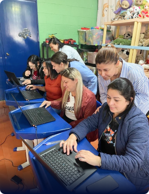 Foto de algumas pessoas estudantes em um momento com o projeto Coda Mundo, a foto mostra alguns alunos sentados mexendo no computador e atrás dele alguns professores e pessoas do time Zup
